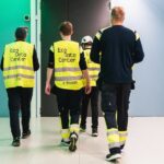 Personer med varselvästar går in i genom en dörr.