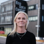 Blond leende kvinna framför en kontorsbyggnad