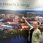 Ann-Britt Jansson framför en väggbild av Hitachi Energys industriområde i Ludvika.
